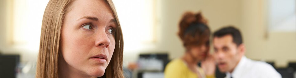 Female student looks troubled by two students looking menacing in the background