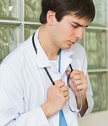 A young male doctor looks stressed in a hallway