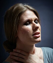 A distraught woman cries and grabs her neck